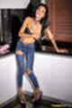 Knees pressed together in jeans arm across her breasts in black bra wearing high heels