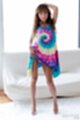 Standing in front of sofa hand on her long hair wearing sunburst dress lifting hem