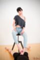 Sitting on stool in jeans giving footjob looking down bare feet