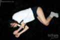 Lying on her side in uniform knees drawn up